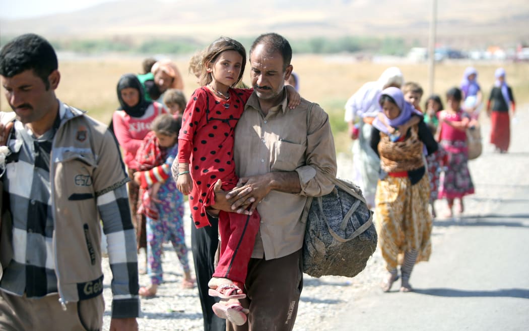 Lines of people from the Yazidi community cross the Iraqi-Syrian border.