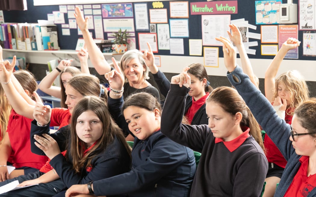 Green Party MP Jan Logie and students at Westport South School raise hands seeking to take a call during a mock parliament debate involving five MPs in a Parliament Outreach visit, 20 November 2022.