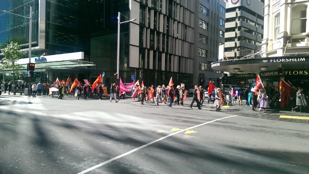 Protesters walking up Queen Street holding placards and chanting.
