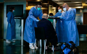 Healthcare workers attend to a COVID-19 patient upon his arrival at the Hotel Melia Barcelona Sarria.