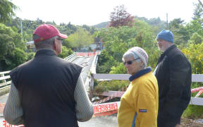 Residents on Bridge Road in Birchville standing near their collapsed bridge over the Akatarawa River.