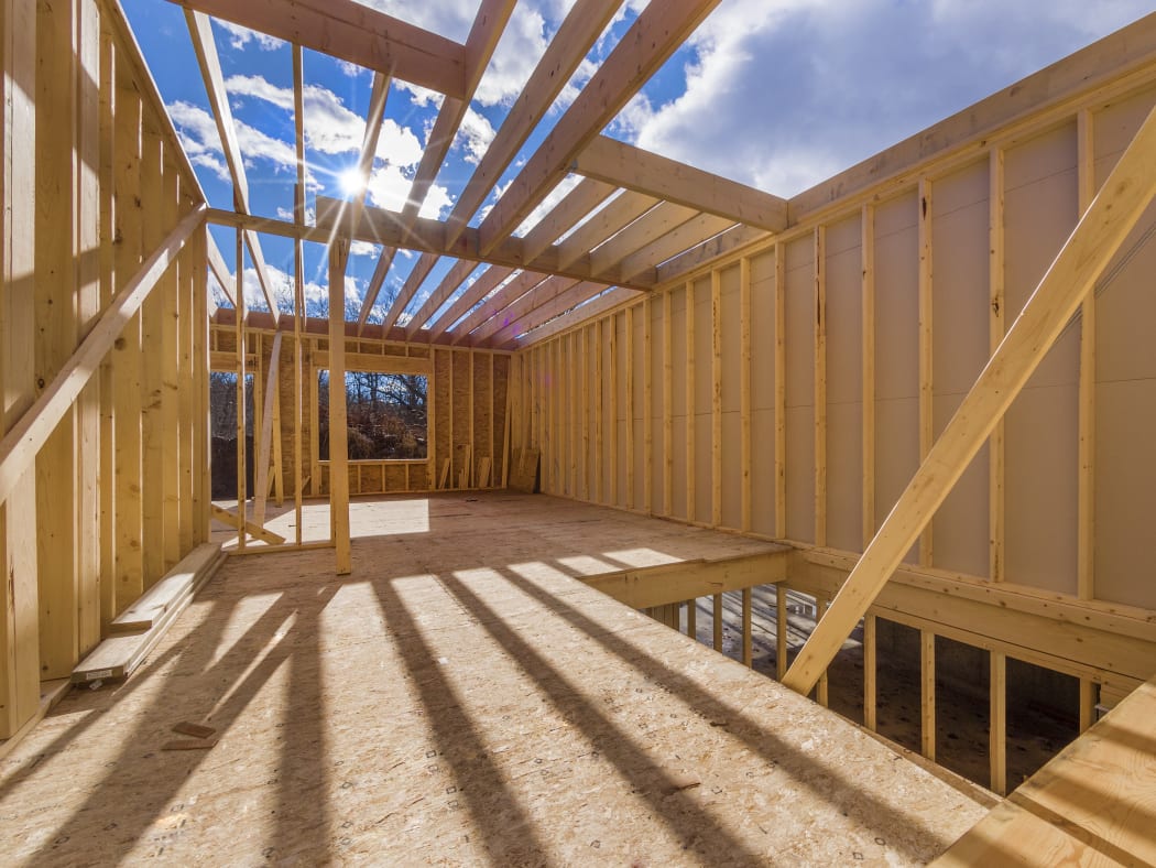 The frame of a new house under construction, with a blue sky behind it (file)