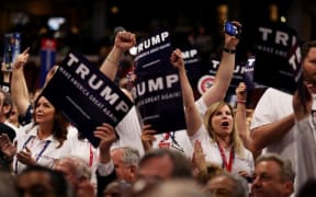 Delegates hold signs in support of Donald Trump during roll call at the Republican National Convention.