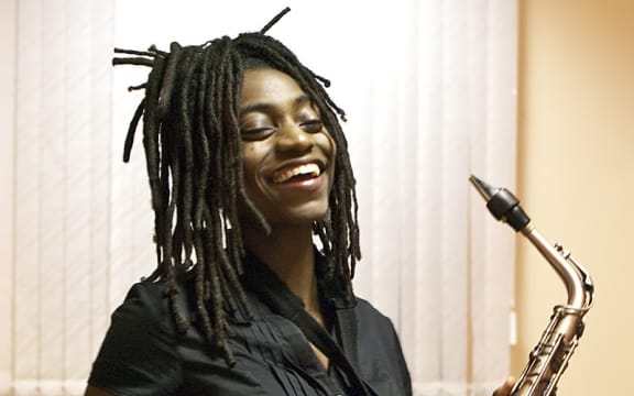 Saxophonist Lakecia Benjamin holding her saxophone and laughing
