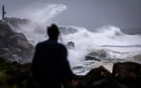 A person watching massive waves stirred up by Tropical Cyclone Alfred break onto the North Wall breakwater in the coastal NSW town of Ballina, on 5 March, 2025.