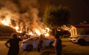People stand next to flames rising from the Ranch fire in the San Gabriel mountains east of Los Angeles.