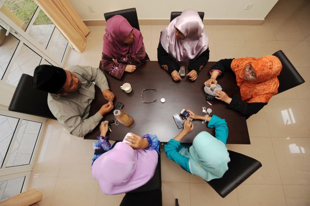 Mohamad Ikram Ashaari talking around a table with his four wives and a child at their home in Putrajaya outside Kuala Lumpur.
