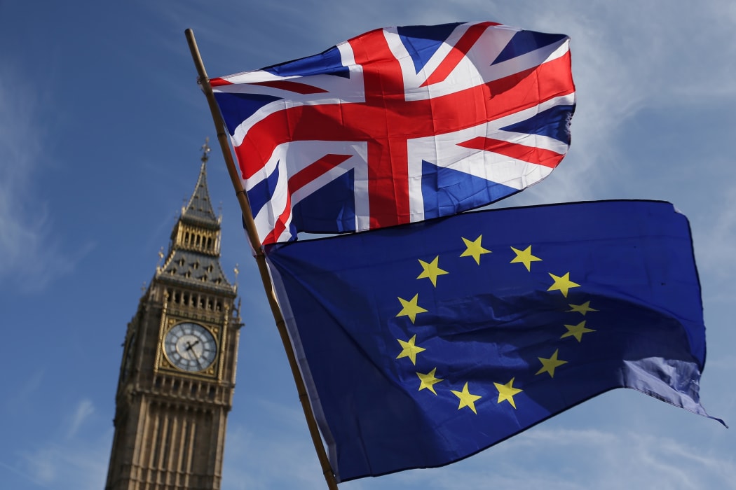 (FILES) In this file photo taken on March 25, 2017 an EU flag and a Union flag held by a demonstrator is seen with Elizabeth Tower (Big Ben) and the Houses of Parliament as marchers taking part in an anti-Brexit, pro-European Union (EU) enter Parliament Square in central London.