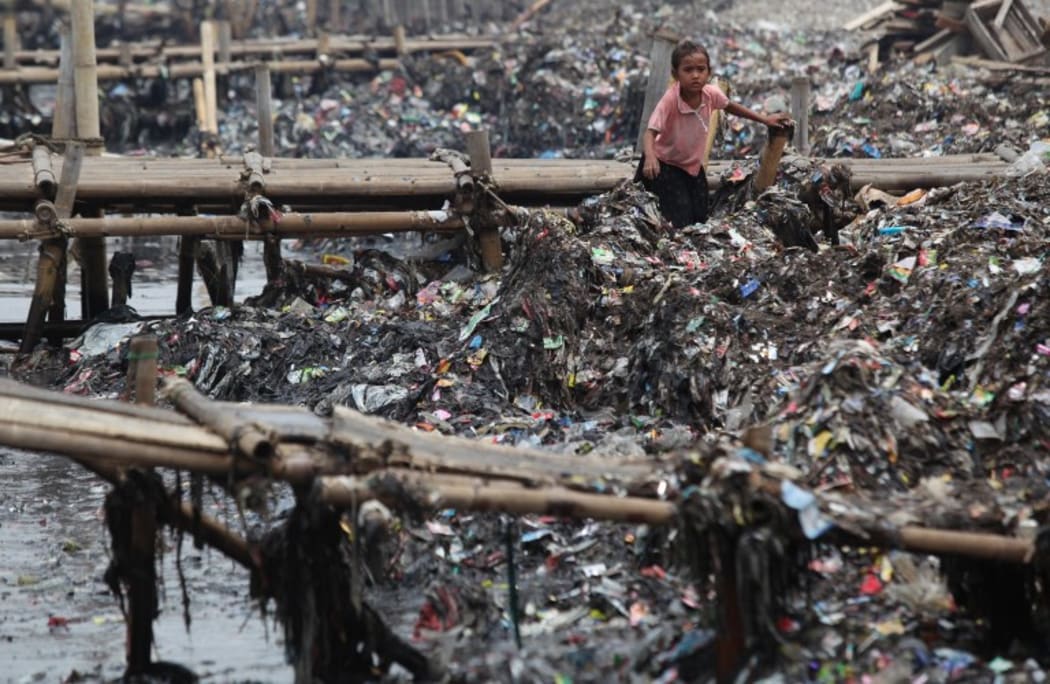 An Indonesian child collects rubbish on the coast near a fishing village in Jakarta, Indonesia.