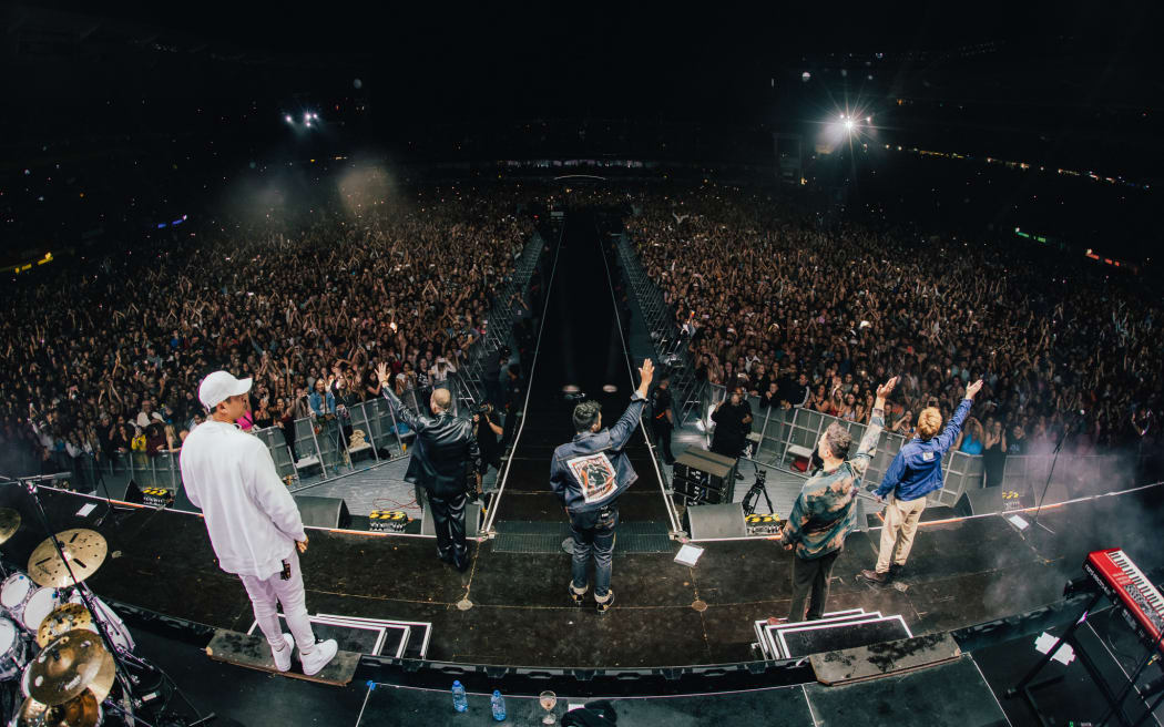 Six60 waving to fans from the stage at Eden Park.