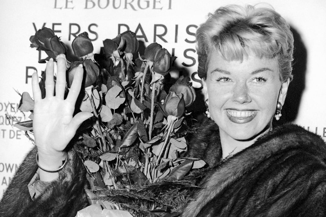 American actress and singer Doris Day holds a bouquet of roses at Le Bourget Airport in Paris in 1955 after flying in from London.