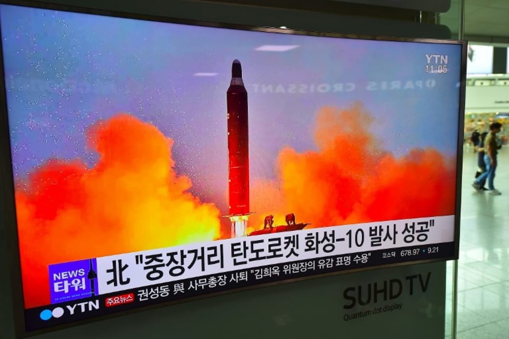 People walk past a television screen reporting news of North Korea's latest Musudan missile test, at a railway station in Seoul on June 23, 2016.