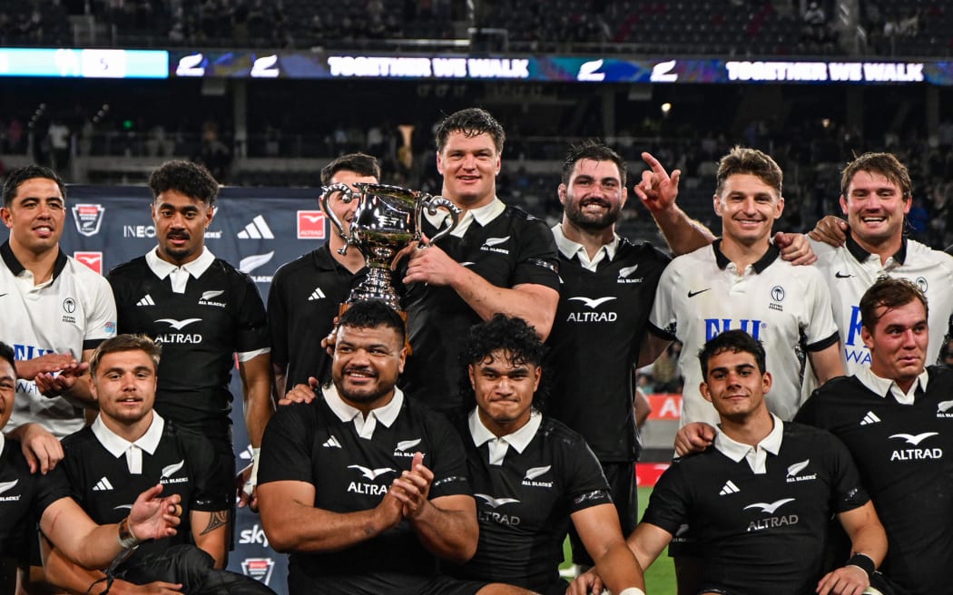 Scott Barrett holds the trophy as New Zealand All Blacks team celebrates.