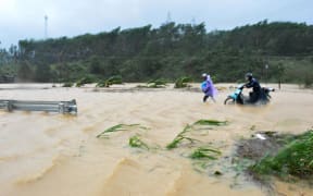 Walking through floodwaters on a highway in the central province of Dak Lak brought by Typhoon Damrey.