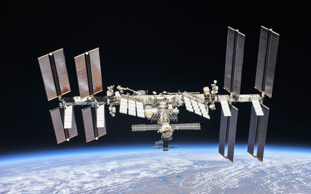 A large spacecraft with "wings" of solar panels above the surface of the Earth.