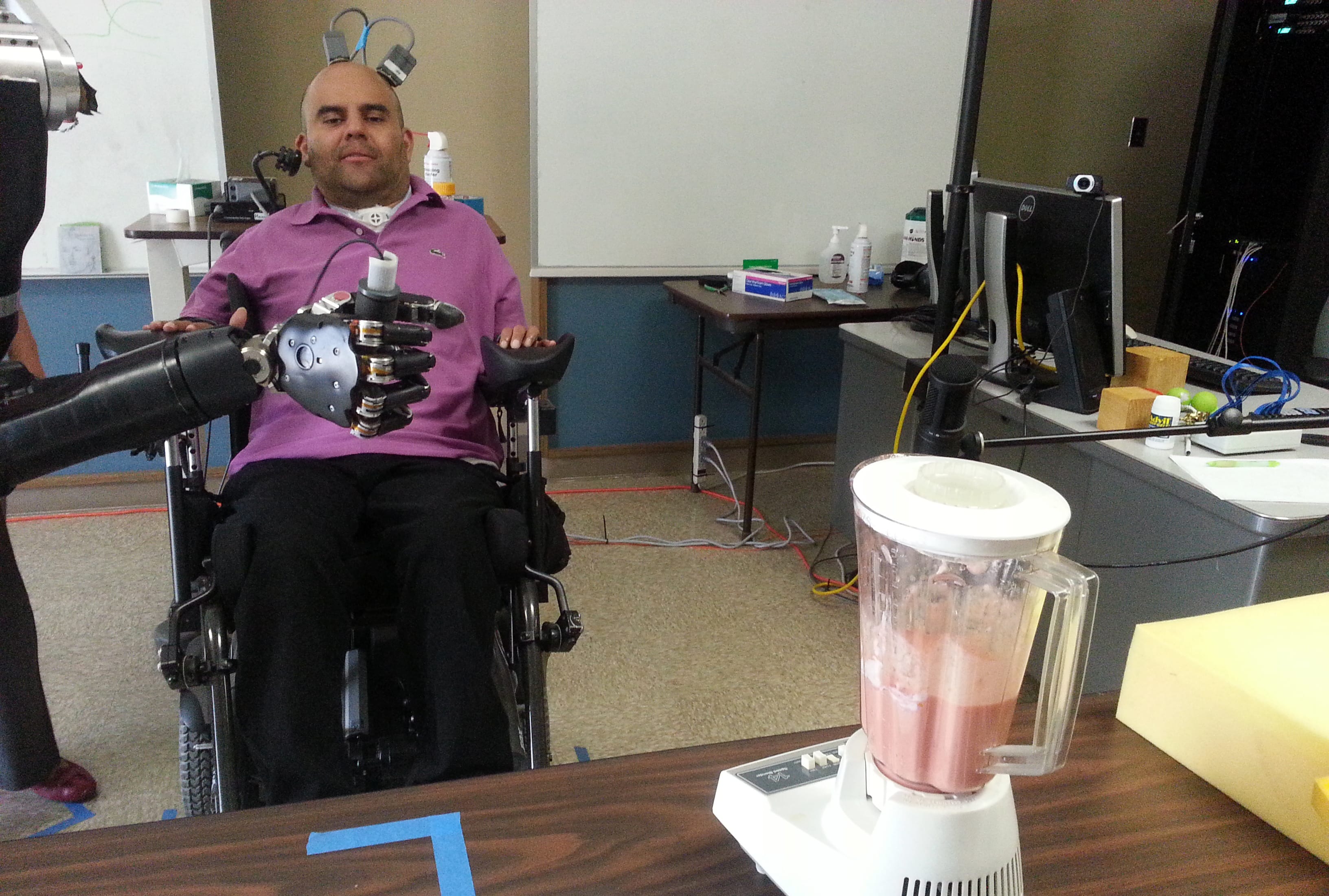 Erik Sorto uses a robotic arm controlled by his thoughts to operate a blender.