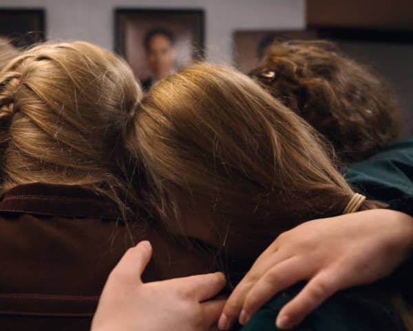 A group of blonde girls hug.