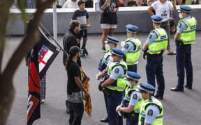 A protester stands in front of police at Parliament.