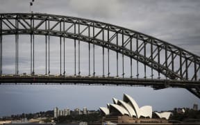 People stand atop of the Sydney Harbour Bridge as ferries sail past the Sydney Opera House during summer on February 11, 2025. (Photo by DAVID GRAY / AFP)