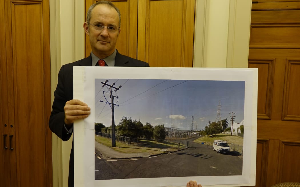 Labour's housing spokesperson Phil Twyford holds an image of a power sub-station in Auckland he says is on Crown land the Government plans for development.