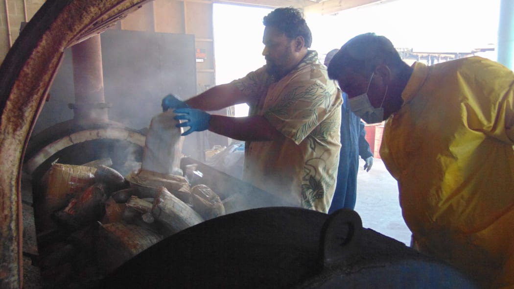 Marshall Islands Police Captain Eric Jorban, left, empties a bag of one-kilo packages of cocaine into an incinerator