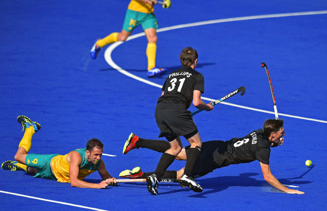 Australia's Mark Knowles and New Zealand's Hayden Phillips and Simon Child vie during the men's hockey match at the Rio Olympics.