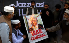 Activists and supporters of the Jamaat-e-Islami party burn a poster of US President Donald Trump during an anti-US and Israel protest in Peshawar on March 2, 2026 after the death of Iran's supreme leader Ayatollah Ali Khamenei amid US-Israel strikes. The death toll from Pakistan's violent weekend protests over the killing of Iran's supreme leader has reached at least 25, according to an AFP tally on March 2. (Photo by Abdul MAJEED / AFP)
