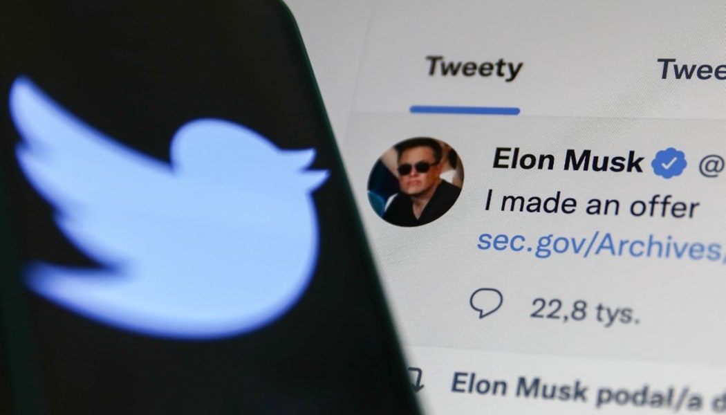 An Elon Musk tweet is displayed on a screen and the Twitter logo is displayed on a phone screen in this illustration photo.