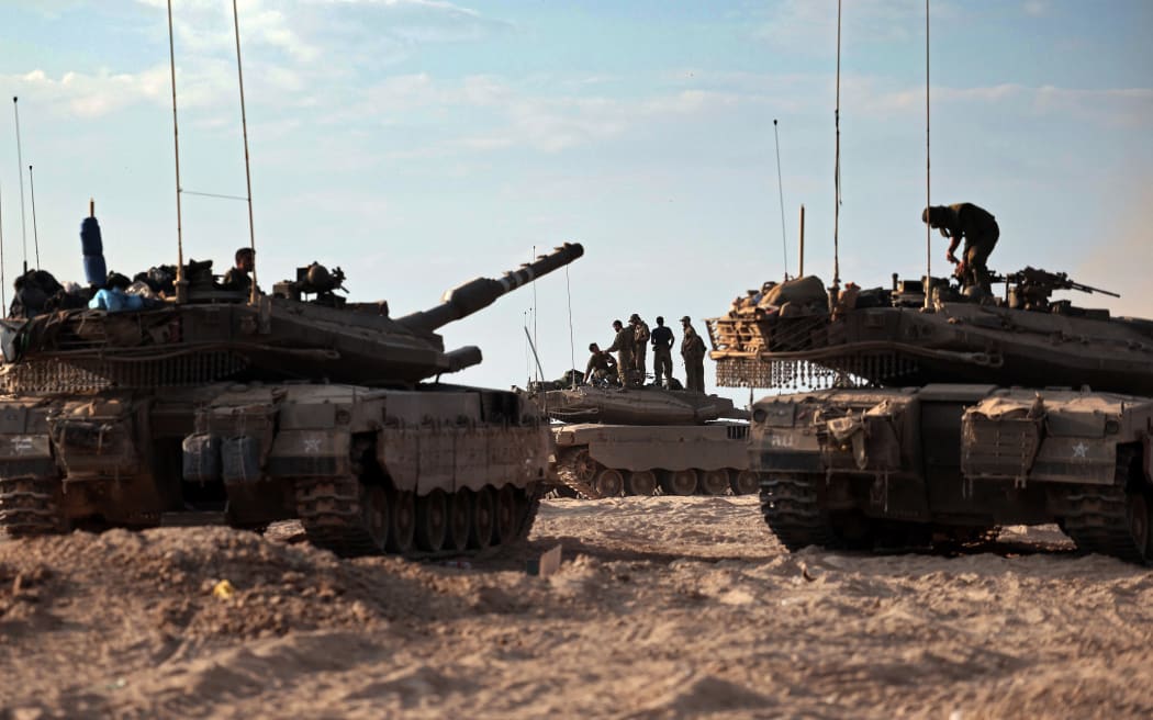 Israeli troops and tanks gather in a field near the kibbutz Beeri in southern Israel on October 14, 2023, close to the spot where 270 revellers were gunned down or burnt in their cars by Hamas gunmen at the Supernova music festival in the Negev desert on October 7. Hamas launched a large-scale attack on Israel on October 7 which killed at least 1300 people, sparking a retaliatory bombing campaign that has killed more than 1900 in the Gaza Strip ahead of a potential Israeli ground invasion of the territory. (Photo by Thomas COEX / AFP)