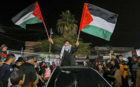 People celebrate along a street at Deir el-Balah in the central Gaza Strip, on January 15, 2025, amid the ongoing war in the Palestinian territory between Israel and Hamas. Crowds of Gazans chanted and embraced on January 15 as news spread that a ceasefire and hostage release deal had been reached between Israel and Hamas aimed at ending more than 15 months of war in the Palestinian territory.