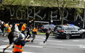 Demonstrators hit a police car during a protest against Covid-19 regulations in Melbourne on September 21, 2021.