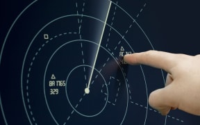 Air traffic controller points to a plane on radar.