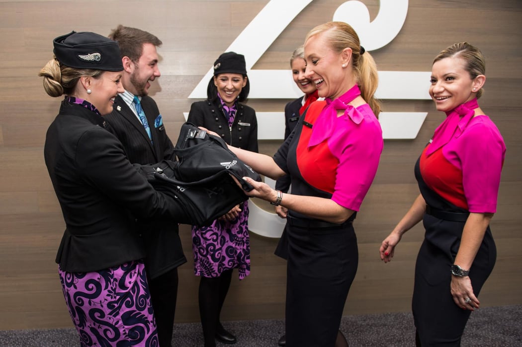 Air New Zealand crew members hand over All Blacks gear to Qantas at Sydney Airport after the Australian airline lost a wager over the 2015 Rugby World Cup.