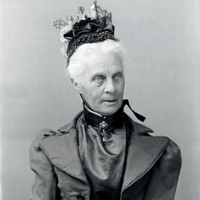 Emily Harris wearing a plaited straw bonnet trimmed with gathered tulle, satin, lace, white flowers and decorations that look like tiny bells. Glass-plate negative, c.1898.