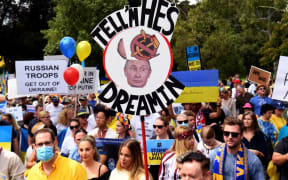 People hold up placards during a march to protest against the Russian invasion of Ukraine, in Melbourne on February 27, 2022.