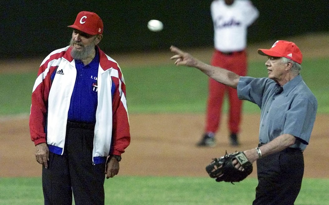 Former US president Jimmy Carter (R) throws the first pitch in a baseball game beside Cuban President Fidel Castro (L) 14 May 2002 in Havana. Carter made a bold push for democratic opening in communist Cuba, urging Castro to let the UN human rights chief visit and calling attention to an unprecedented dissident bid for political change. (Photo by Adalberto ROQUE / AFP)