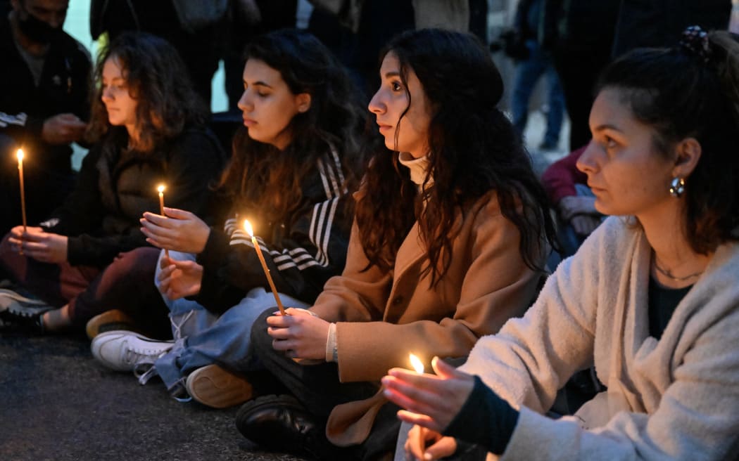 Students hold candles outside the Hellenic Train headquarters in Athens on 1 March, 2023, during a tribute to the victims of a deadly train crash near the city of Larissa, central Greece. The Greek government announced 3 days of national mourning.