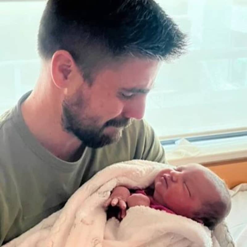 A man close to tears cradles a newborn baby.