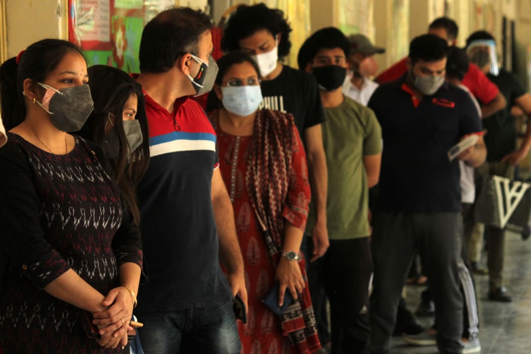 People line up to receive their first dose of Covishield, a Covid-19 vaccine manufactured by Serum Institute of India, at a government school in New Delhi, 3 May 2021.