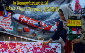 A Pakistani civil society activist places a candle during a vigil for the victims of AirAsia Flight QZ8501.
