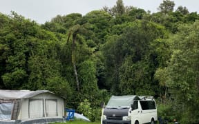 Campers shelter beneath the Pukemiro Pā and Puketapu Pā at Onaero Bay.