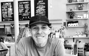 Pete sits across a table at a cafe, smiling.