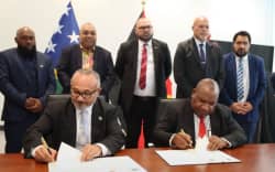 The prime minister of Solomon Islands Matthew Wale (left) and his PNG counterpart James Marape (right) sign a Framework Agreement on Development and Economic Cooperation, watched on by members of PNG’s cabinet, during talks in Port Moresby, 26 June 2026.