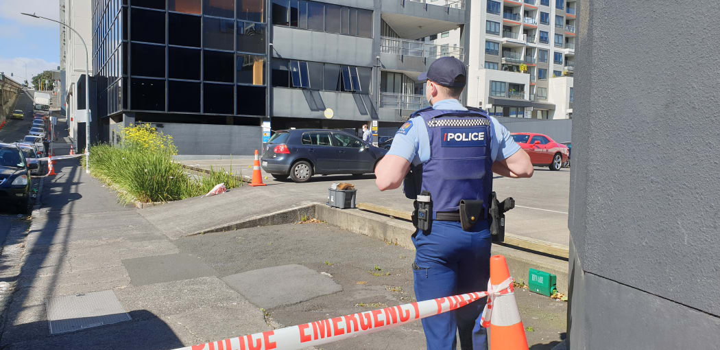 A police officer on Nelson St, Auckland, after a man suffered a minor gunshot injury and a vehicle was found with bullet holes.