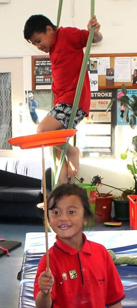This is an image of two boys using the aerialist rope  and spinning  the plate on a stick