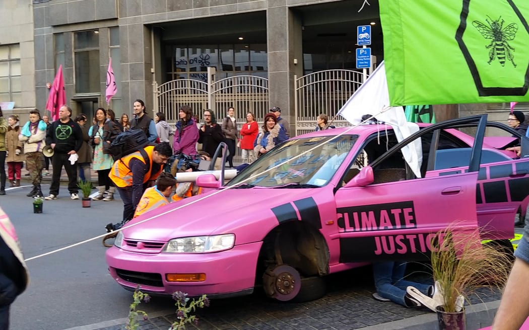 Extinction Rebellion protesters have blocked off Stout St in central Wellington, in a bid to cause disruptions outside MBIE's office.