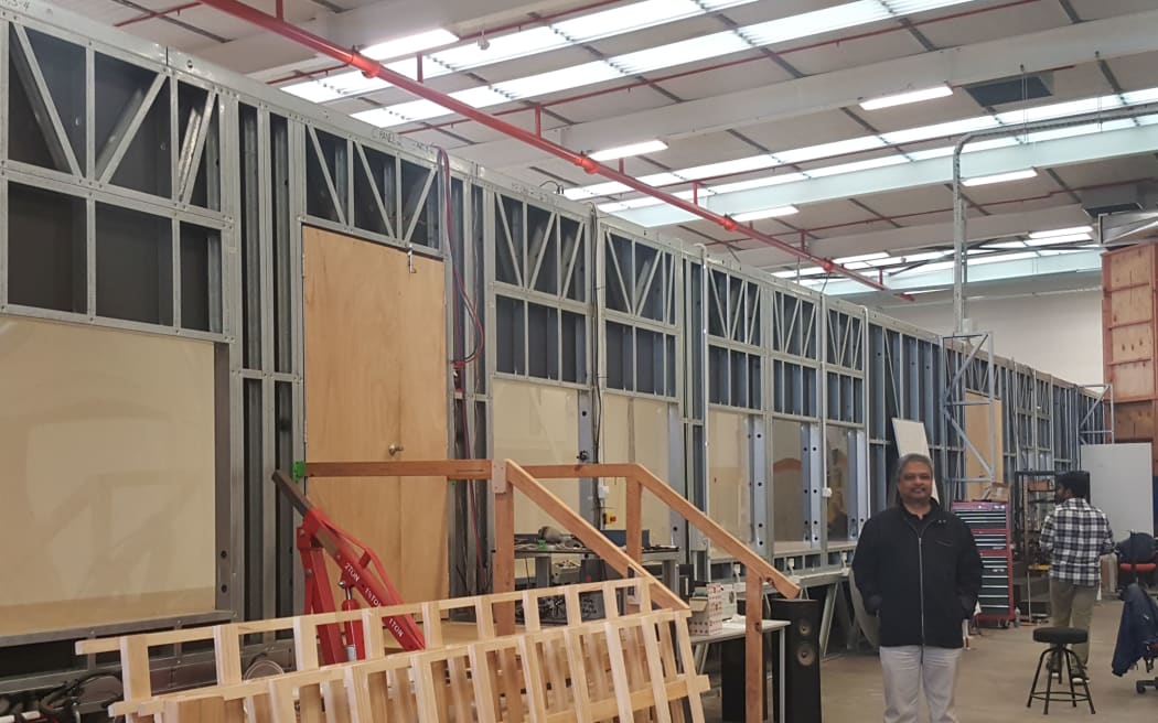 Aerodynamics researcher Rajnish Sharma stands beside the 20-metre long boundary layer wind tunnel at the University of Auckland. The wooden structure to the right is a smaller vertical wind tunnel.
