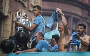 Manchester City's Spanish midfielder Rodri holds the European Cup as he celebrates with teammates their three trophies including the FA Cup and the Premier League ones during an open-top bus victory parade in the streets of Manchester, 2023.