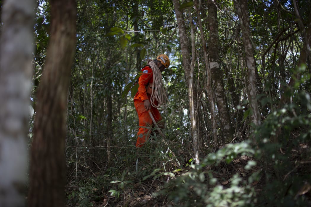 A firefighter opens an escape route during the search for victims of Friday's dam collapse.
