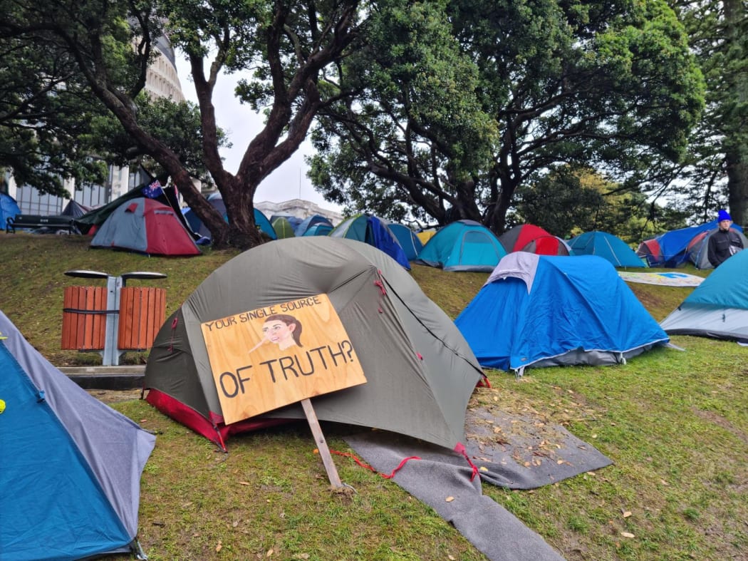 A sign leans against a tent at the protest camp at Parliament.